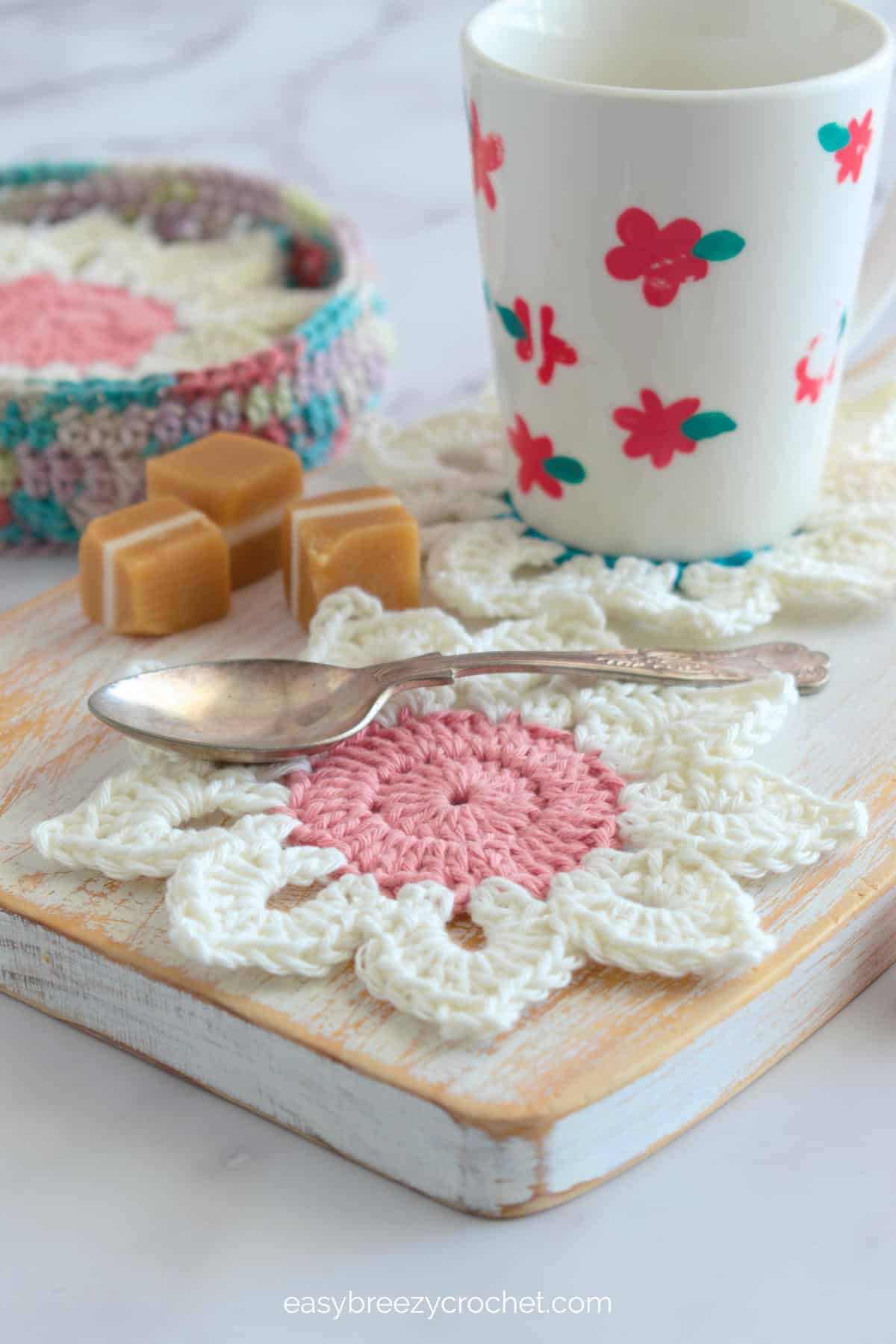 White sunflower coaster with pink center and a red and white cup.