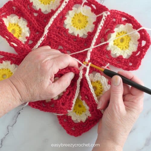 Red granny squares joined together with white yarn and single crochet stitches.