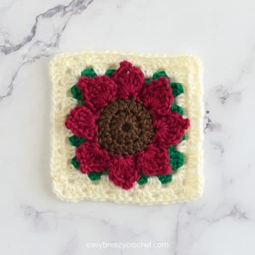 A dark red crocheted 3d sunflower granny square.