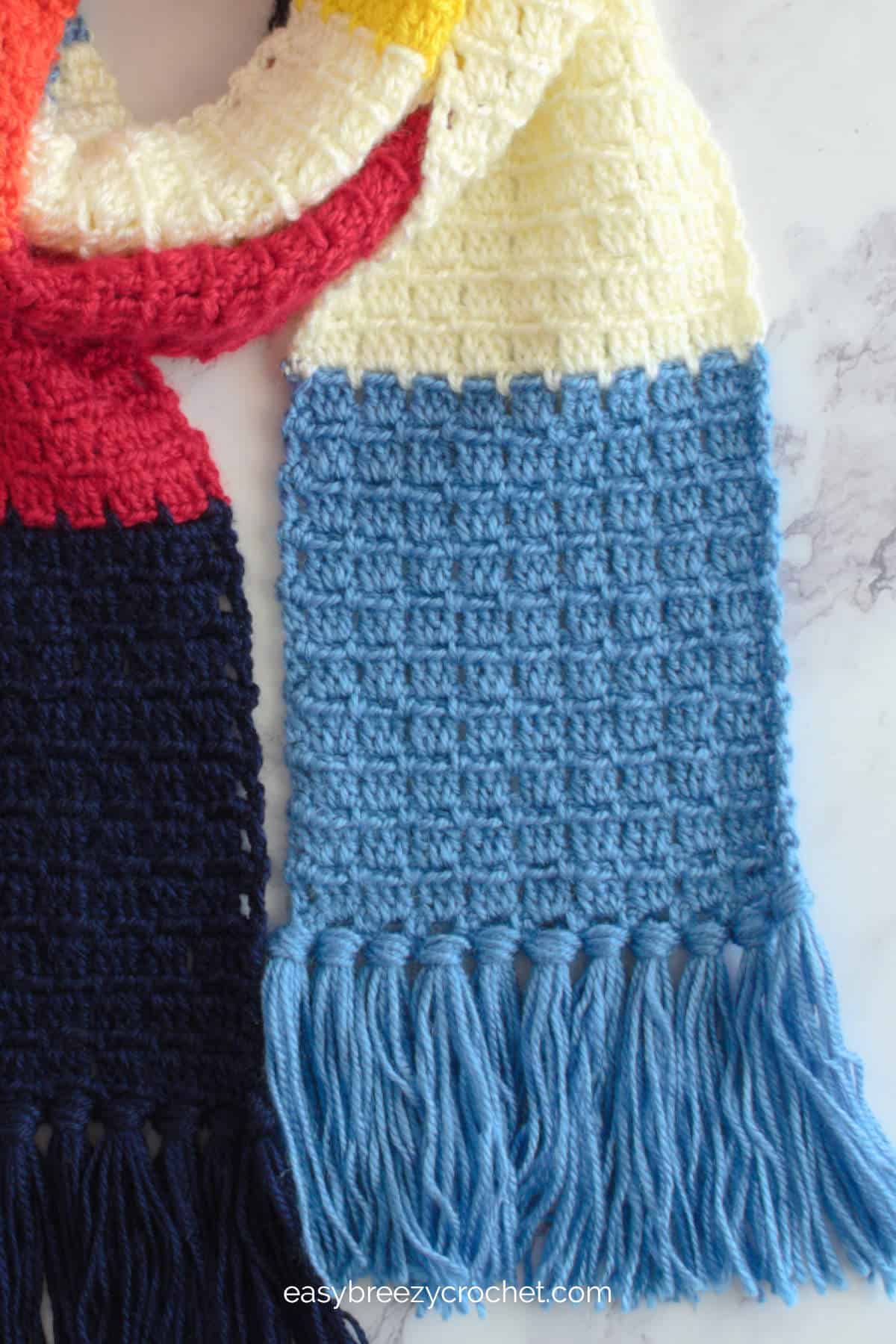 A closeup of the block stitch scarf with a fringe.
