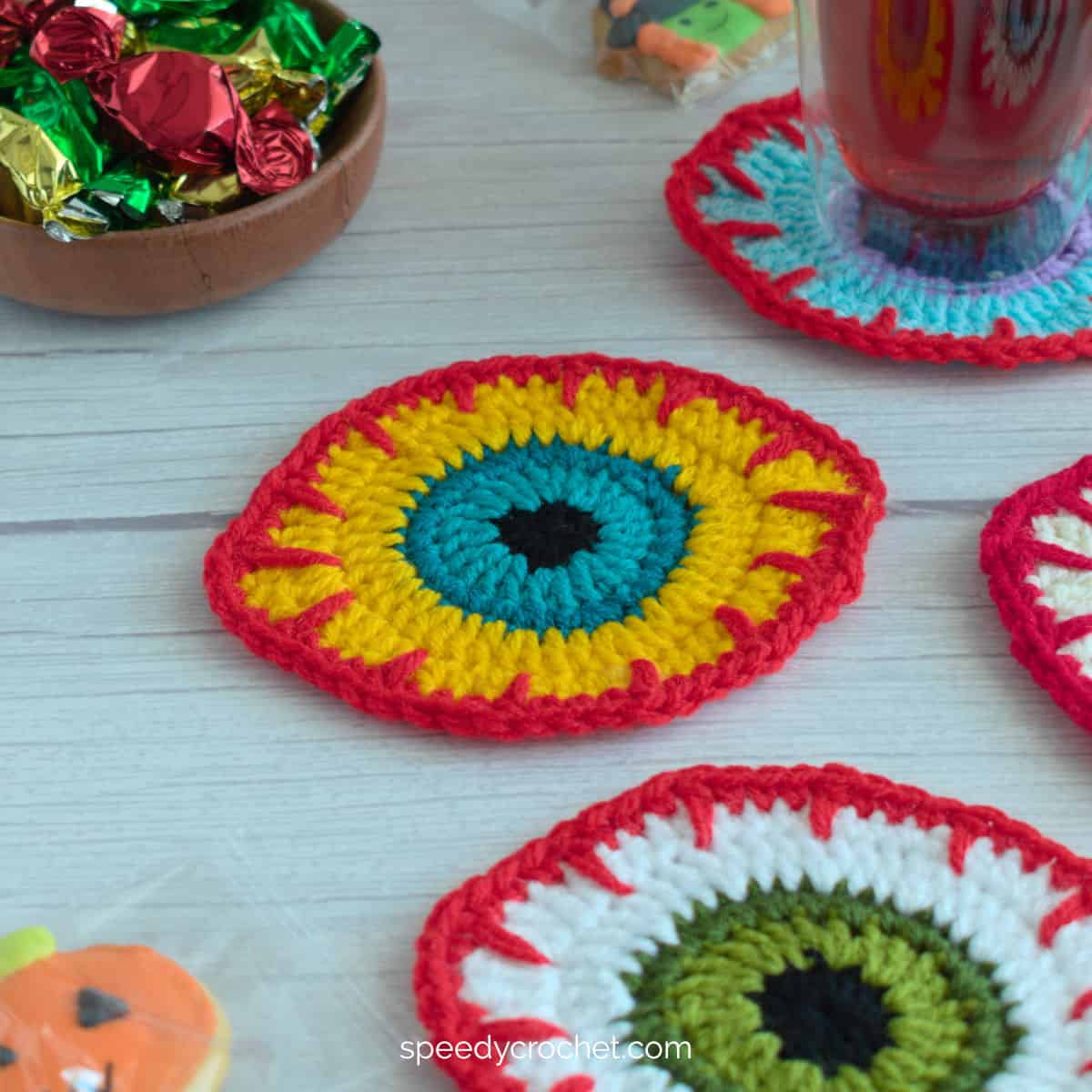 A yellow and red crochet eyeball coaster.
