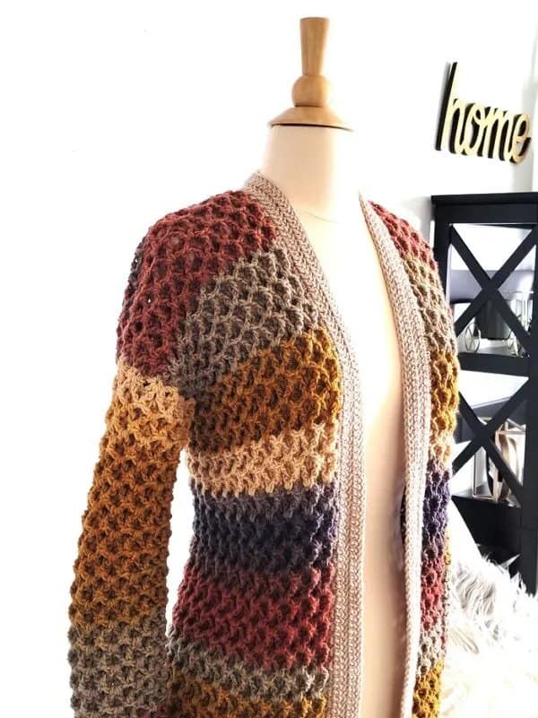 A multi colored crocheted cardigan displayed on a dress makers dummy.