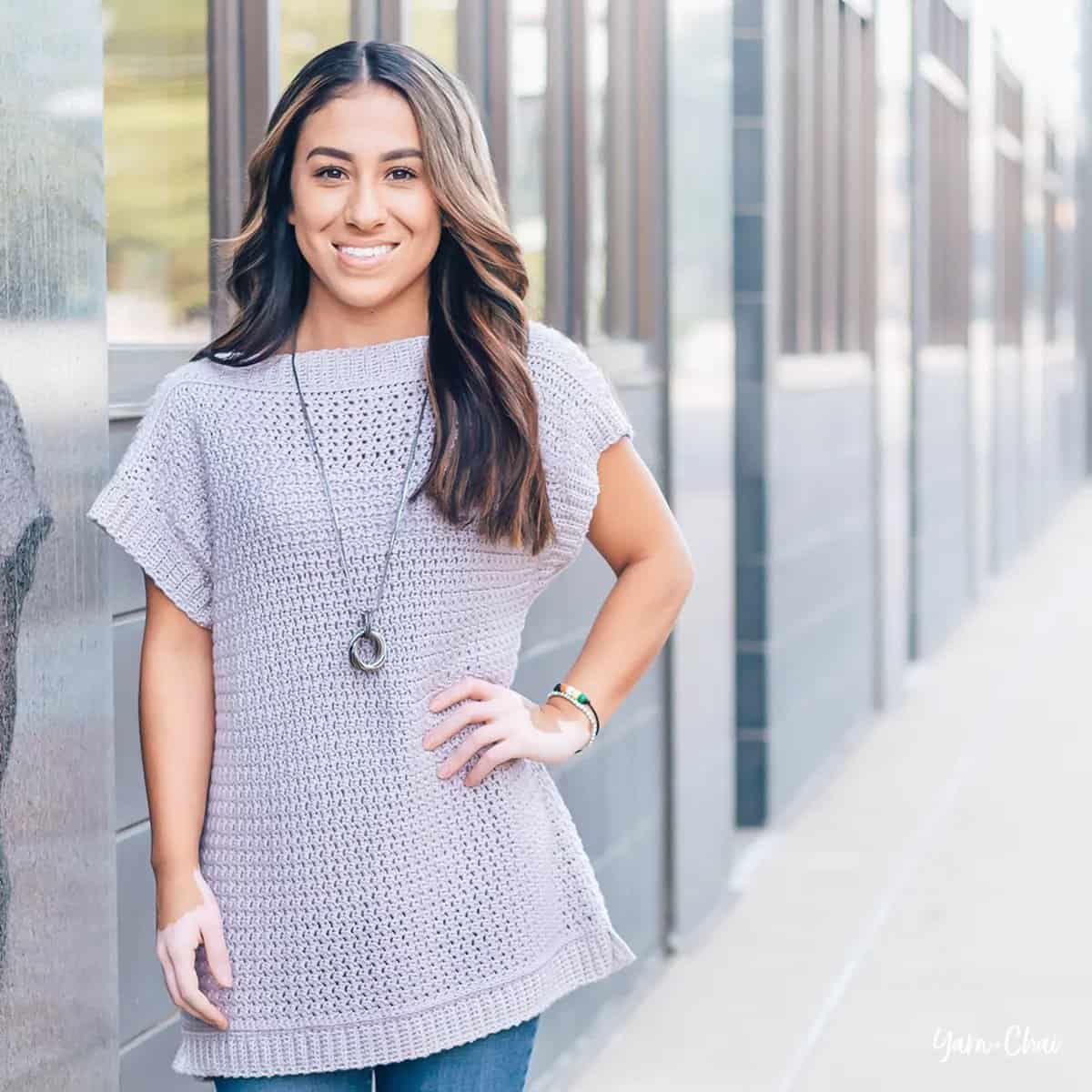 A smiling lady in a short sleeved crochet sweater.