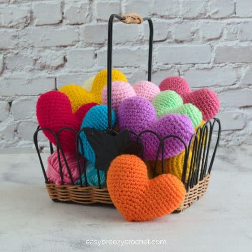 A close up of crocheted hearts in a basket.