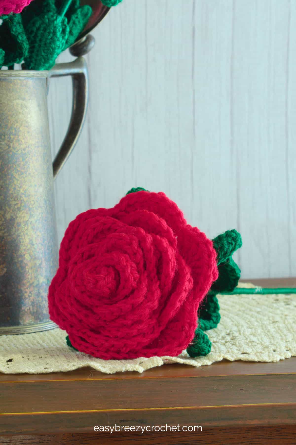 A close up of a single red crocheted rose.
