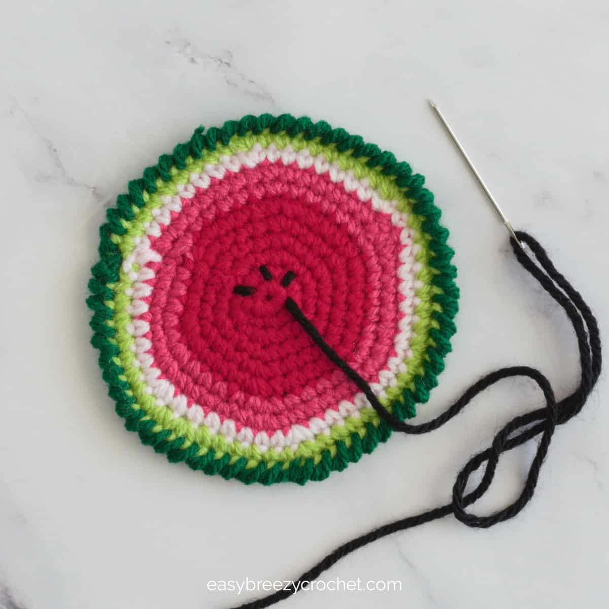 A partially completed crochet watermelon coaster.