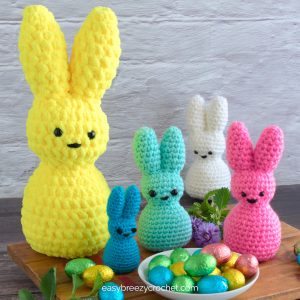 A bunch or multi colored crochet peep bunnies with Easter eggs.