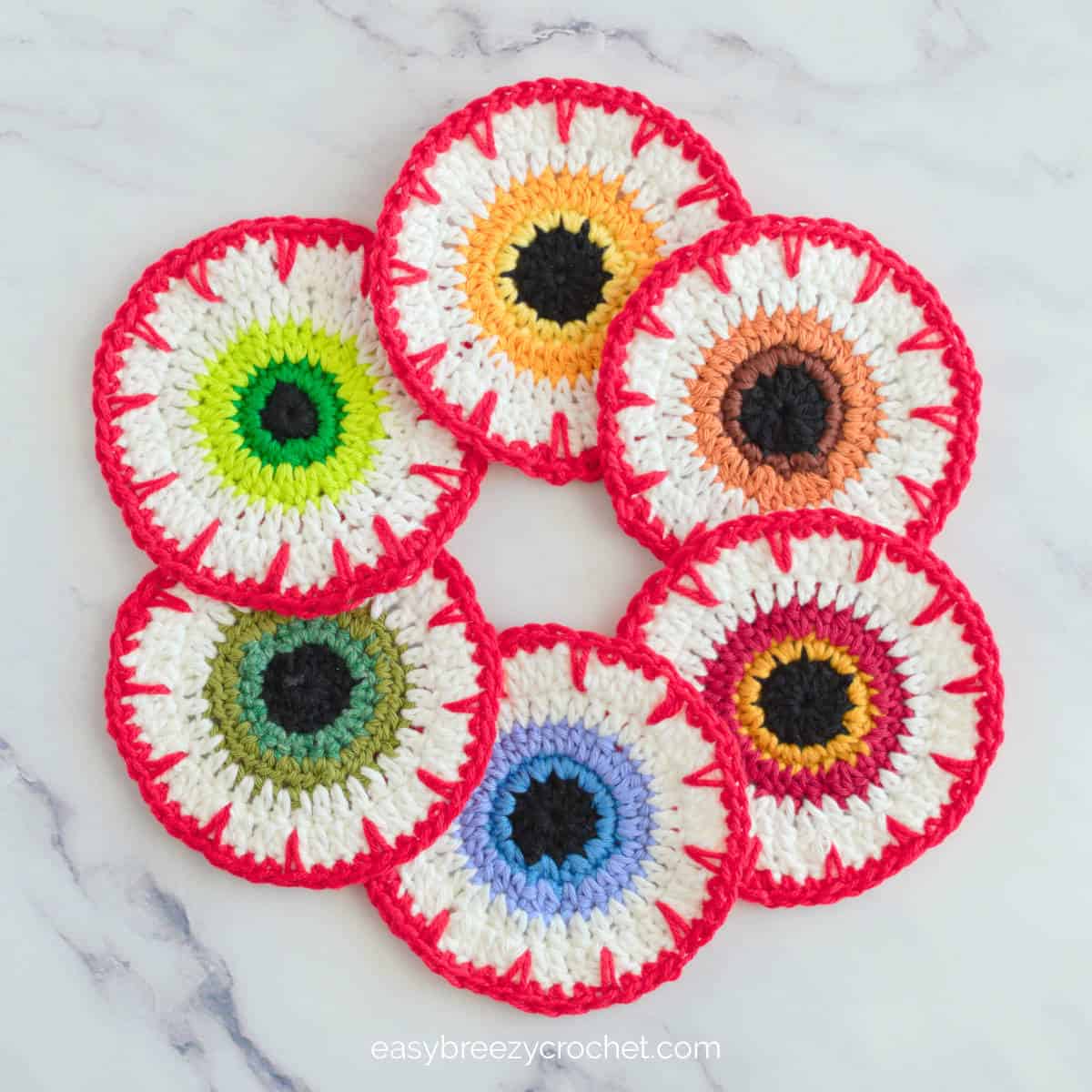 A top down view of six crochet eyeball coasters.