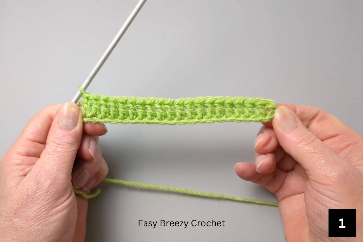 Hands holding a single row of double crochet stitches.
