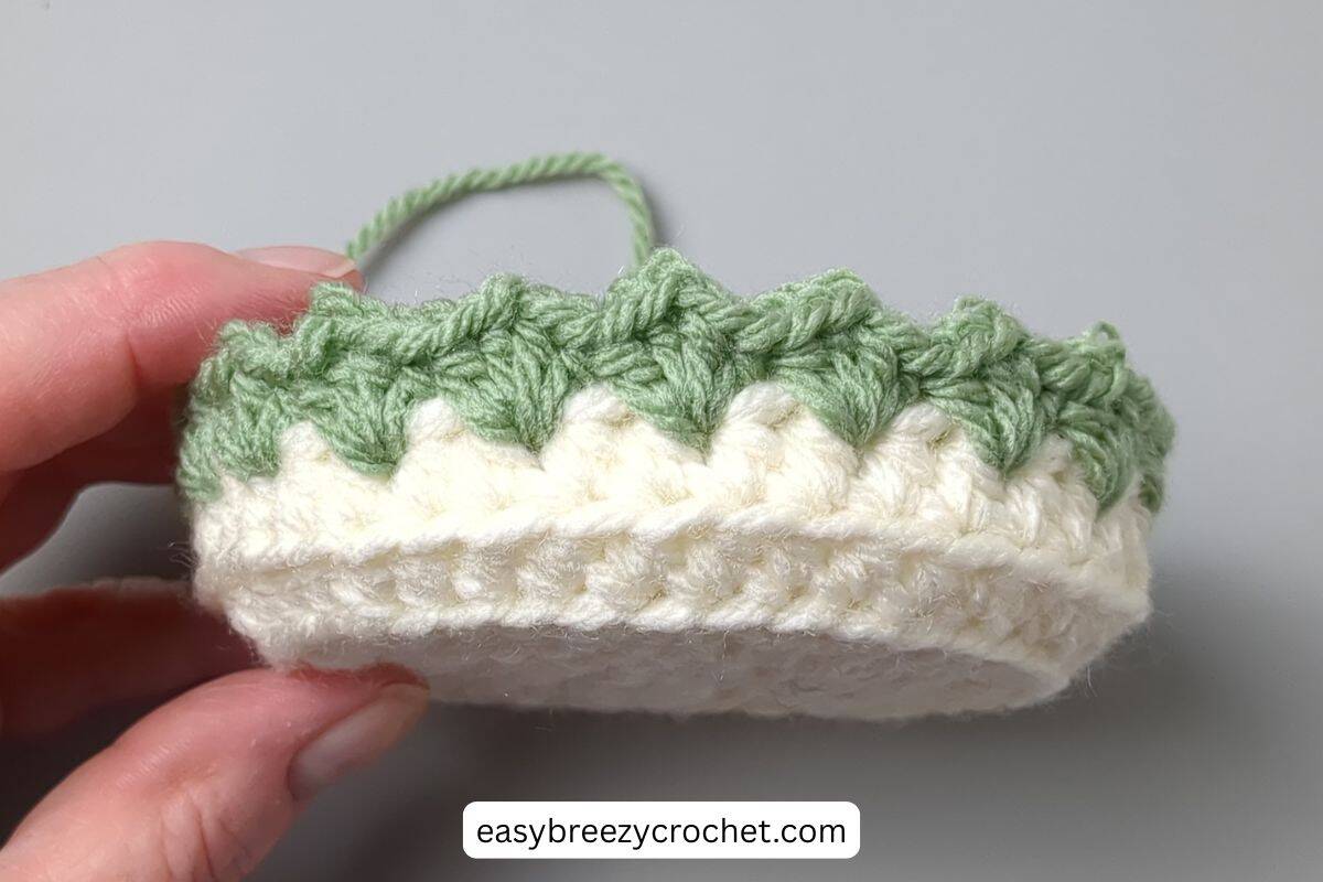 A crochet basket with a green crochet edge.