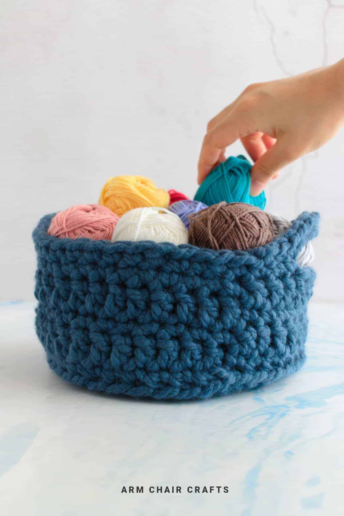 A blue crochet basket filled with yarn.