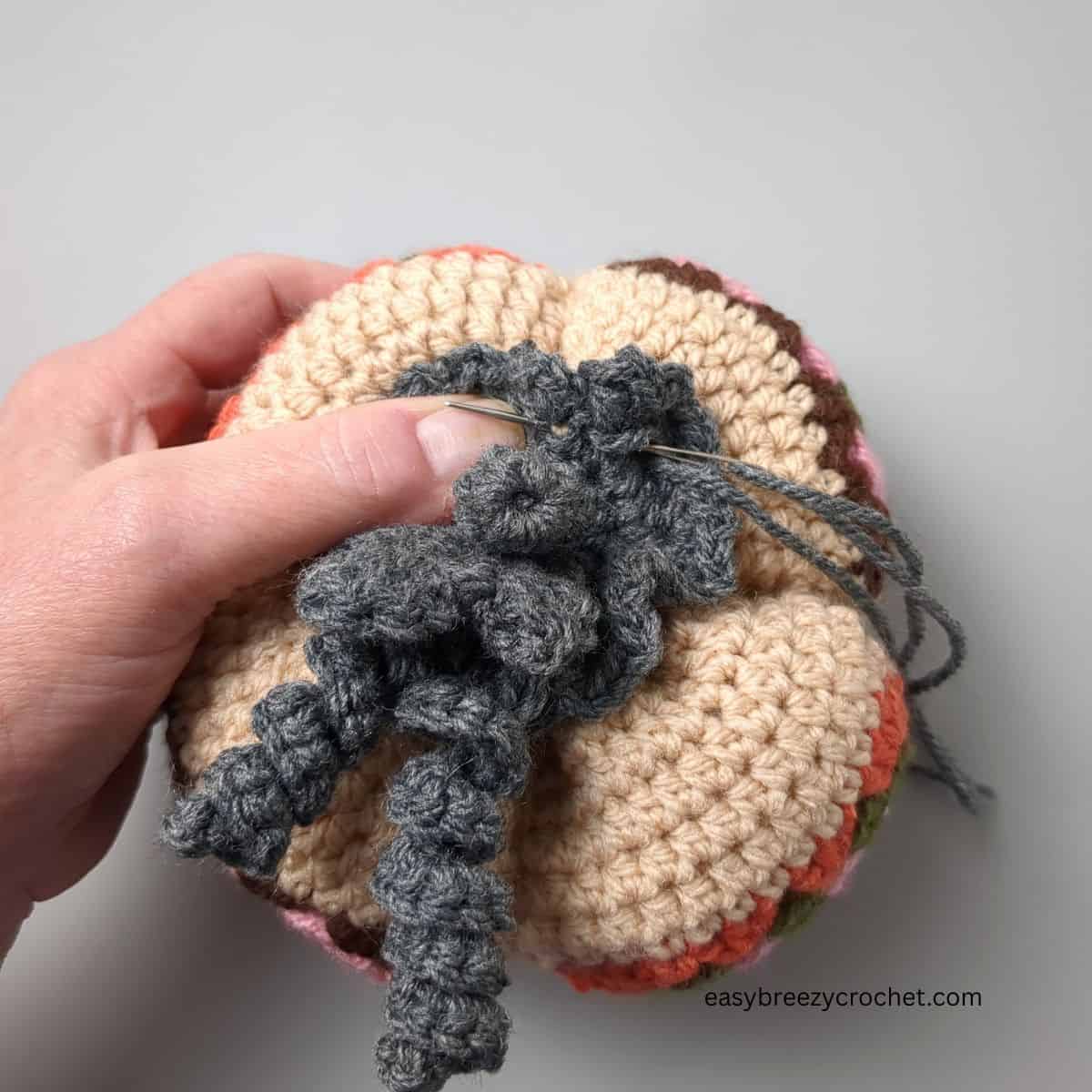 Attaching stem to top of crochet pumpkin.
